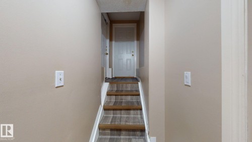 Staircase featuring wood-finish flooring treads and risers, complemented by neutral tone walls - 3738 28A Street, Edmonton, AB 