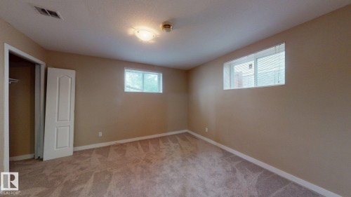 Neutral-toned room featuring plush carpeting, two windows, and a ceiling-mounted light fixture - 3738 28A Street, Edmonton, AB 