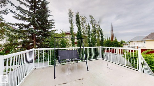 Spacious outdoor deck featuring a light-colored surface, white railing, and mature surrounding trees - 3738 28A Street, Edmonton, AB 