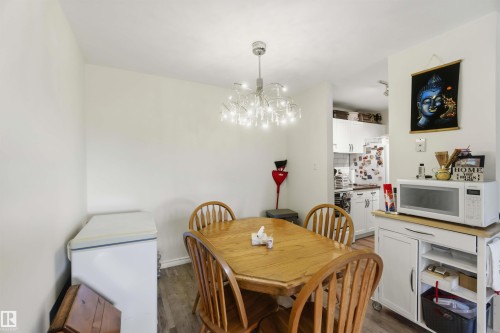 Dining area featuring wood-finish flooring, a modern chandelier, and neutral wall tones - 204 4601 131 Avenue, Edmonton, AB 