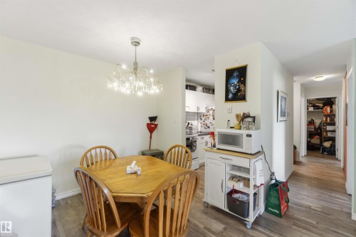 Dining area featuring wood-finish flooring, a contemporary chandelier, and light-toned walls - 204 4601 131 Avenue, Edmonton, AB 
