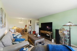 Spacious living area featuring wood-finish flooring, a light green accent wall, and recessed lighting - 