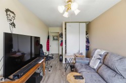 Living area featuring wood-finish flooring, a ceiling fan with light fixture, and a built-in closet with sliding doors - 