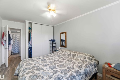 Bedroom featuring wood-finish flooring, white crown molding, and a ceiling fan with light fixture - 204 4601 131 Avenue, Edmonton, AB 
