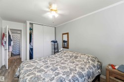 Bedroom featuring wood-finish flooring, white crown molding, and a ceiling fan with light fixture - 