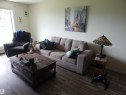 Open-concept living area featuring wood-finish flooring, light-toned walls, and a large window with natural light - 204 4601 131 Avenue, Edmonton, AB 