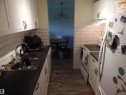 Galley kitchen featuring white cabinetry, dark countertops, a subway tile backsplash, stainless steel sink, and wood-finish flooring - 204 4601 131 Avenue, Edmonton, AB 