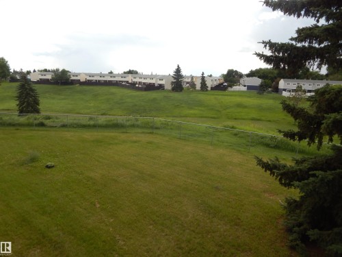 Expansive green space featuring a sloped terrain and distant residential structures - 204 4601 131 Avenue, Edmonton, AB 