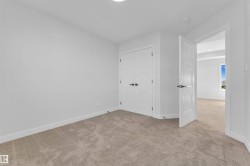 Carpeted room featuring white walls, a built-in closet with double doors, and modern matte black hardware - 