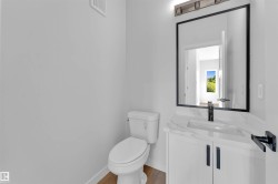 Bathroom featuring a white vanity with black hardware, a rectangular undermount sink, and a countertop with subtle veining - 