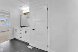Bathroom featuring a dual vanity with white cabinetry, black hardware, and a white countertop - 