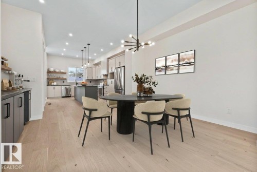 Open-concept kitchen and dining area featuring light wood-finish flooring, recessed lighting, and a contemporary chandelier - 10932 132 Street, Edmonton, AB - Indoor