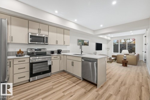 Modern kitchen featuring stainless steel appliances, light-toned cabinetry, and wood-finish flooring - 10932 132 Street, Edmonton, AB - Indoor Photo Showing Kitchen