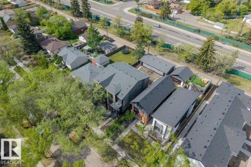 Aerial perspective showcasing multiple properties with dark shingle roofs, surrounded by mature trees - 10932 132 Street, Edmonton, AB - Outdoor With View