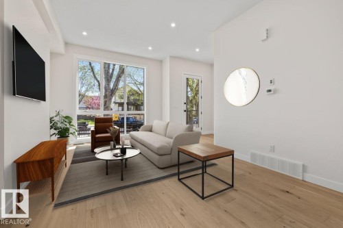 Spacious living area featuring light wood-finish flooring, recessed lighting, and a large picture window - 10932 132 Street, Edmonton, AB - Indoor Photo Showing Living Room