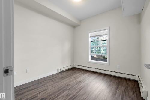 Room with wood-finish flooring, light-toned walls, and a single window with blinds - #209 10611 117 St Nw, Edmonton, AB - Indoor Photo Showing Other Room
