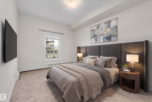 Carpeted room with a wall-mounted television, a single window with blinds, and a built-in upholstered headboard - #209 10611 117 St Nw, Edmonton, AB - Indoor Photo Showing Bedroom