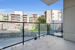 Private balcony with concrete flooring, glass railing, and red handrail accents - 
