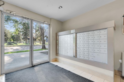 Entry vestibule featuring a wall of individual mailboxes, dual glass entry doors, and overhead lighting - #209 10611 117 St Nw, Edmonton, AB - Indoor Photo Showing Other Room
