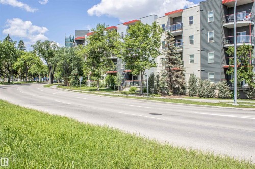 Modern multi-story building featuring grey and white exterior siding with red accent trim - #209 10611 117 St Nw, Edmonton, AB - Outdoor With Balcony