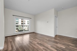 Spacious interior featuring wood-finish flooring, light-toned walls, and a sliding glass door leading to a private balcony - 