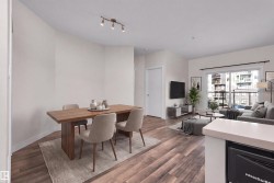 Open-concept living space featuring wood-finish flooring, a sliding glass door leading to a balcony, and a track lighting fixture - 