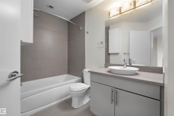 Bathroom featuring a white vanity with an undermount sink, a countertop, and a large mirror - 