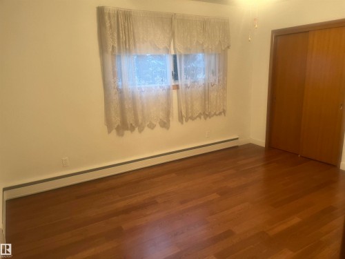 Room featuring wood-finish flooring, a window with natural light, and sliding closet doors - 8736 72 Street Nw, Edmonton, AB - Indoor Photo Showing Other Room