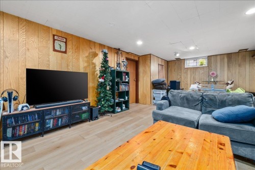 Recreation area featuring wood-panel walls, light wood-finish flooring, and a drop ceiling with recessed lighting - 8736 72 Street Nw, Edmonton, AB - Indoor Photo Showing Basement