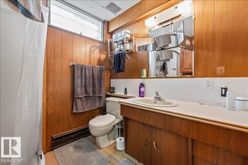 Bathroom featuring wood paneling, a single vanity with integrated sink, and a built-in medicine cabinet - 8736 72 Street Nw, Edmonton, AB - Indoor Photo Showing Bathroom