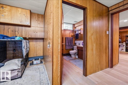 Wood-finish paneling throughout, featuring built-in cabinetry, a ceiling with acoustic panels, and wood-finish flooring - 8736 72 Street Nw, Edmonton, AB - Indoor