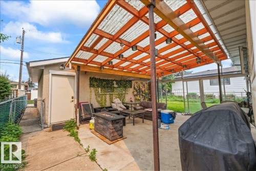 Concrete patio featuring a wood-frame translucent roof structure with integrated lighting - 8736 72 Street Nw, Edmonton, AB - Outdoor With Deck Patio Veranda