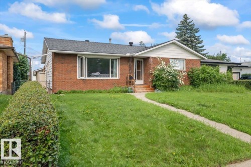 Brick exterior featuring a gabled roofline and an expansive front lawn - 8736 72 Street Nw, Edmonton, AB - Outdoor