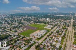 Aerial perspective showcasing a residential neighborhood with tree-lined streets, a large green space, and surrounding urban development - 