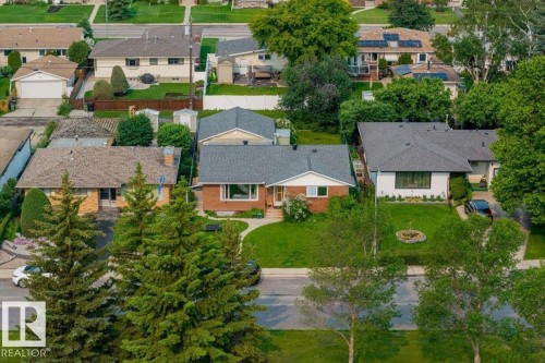 Traditional brick exterior featuring a grey shingle roof, established front lawn, and paved driveway - 8736 72 Street Nw, Edmonton, AB - Outdoor