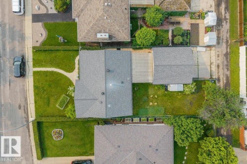 Aerial perspective showcasing a property with a grey shingle roof, a detached garage, and a lush green lawn - 8736 72 Street Nw, Edmonton, AB - Outdoor