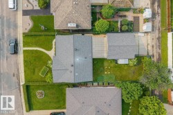 Aerial perspective showcasing a property with a grey shingle roof, a detached garage, and a lush green lawn - 