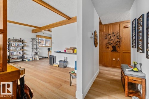Open concept living space featuring wood-finish flooring, exposed ceiling beams, and a window with a wood trim - 8736 72 Street Nw, Edmonton, AB - Indoor Photo Showing Other Room