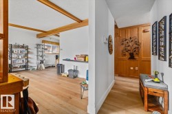 Open concept living space featuring wood-finish flooring, exposed ceiling beams, and a window with a wood trim - 