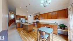 Kitchen featuring wood-finish flooring, wood cabinetry, stone countertops, and stainless steel appliances - 