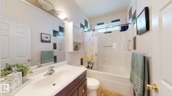 Bathroom featuring a dark wood-finish vanity with a single basin, an integrated white countertop, and a white shower-over-tub combination with a window - 