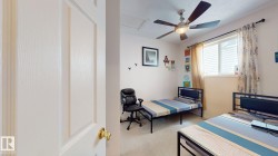 Bedroom featuring a ceiling fan with integrated lighting, a window with horizontal blinds, and neutral-toned walls - 