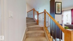 Carpeted staircase with light wood handrails and black metal balusters - 