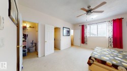 Bedroom featuring a window with white trim, a ceiling fan with light fixture, light-colored carpet, and two interior doors - 