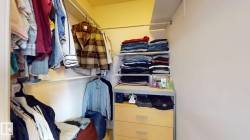 Walk-in closet featuring extensive built-in shelving, multiple hanging rods, and an integrated wood-finish drawer unit - 