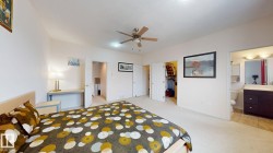 Carpeted room featuring a ceiling fan with integrated lighting, a built-in desk, and two closet entries with bi-fold doors - 