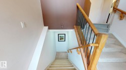 Staircase featuring light wood handrails, dark metal balusters, and carpeted treads - 