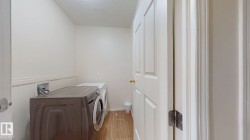 Dedicated laundry space featuring wood-finish flooring and neutral wall tones - 
