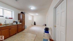 Lower-level area featuring a functional kitchenette with wood cabinetry and granite-style countertops - 