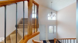 Two-story entryway with a vaulted ceiling, chandelier lighting, and a transom window - 